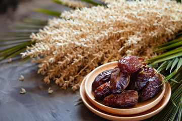 Bowl of raw organic medjool dates with leaves and flowers of date palm