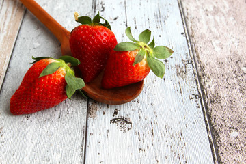 Fresh ripe strawberries with wooden spoon on wooden board, high angle view