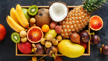 Fresh exotic fruit in a box. Golden pineapple, blood orange, coconut, mini bananas, longan.