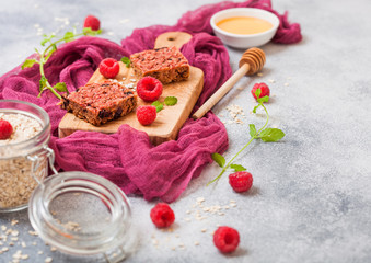 Organic cereal fruit granola bar with berries on vintage board with honey spoon and jar of oats on purple cloth. Strawberry, raspberry and blueberry with mint leaf and bowl of honey