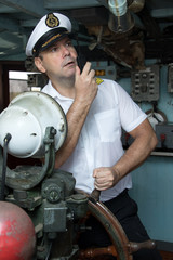 Navigation officer manage ship with transmitter. Captain standing in the wheelhouse is steering the ship with a rudder. © milkovasa