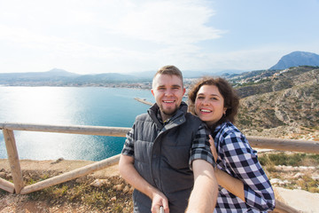 Travel, vacation and holiday concept - Happy couple taking selfie over beautiful landscape