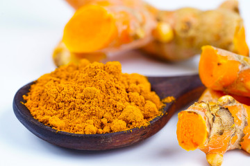 Turmeric roots and powder herb on wooden background.