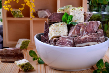 Halva and sherbet in a bowl against the wooden background. Assortment of oriental desserts