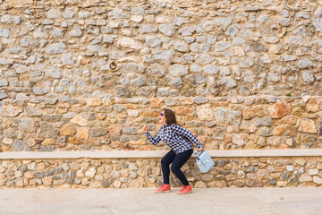 Emotions and gestures - Portrait of funny woman running away on stone wall background