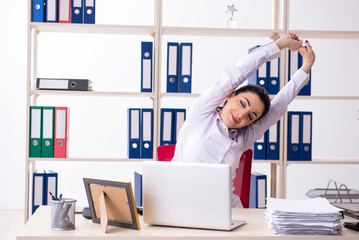 Young female employee doing exercises in the office 