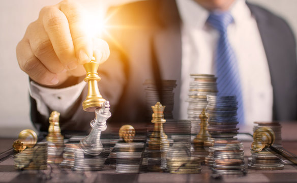 Successful planning and strategic concept, business man holding chess and move forward for win and victory with staked money coins