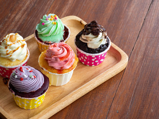 Colorful of homemade cupcake in wooden Tray on wooden table.