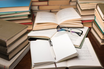 Open book and glasses on wood desk in the library room with blurred focus for education background and back to school concept