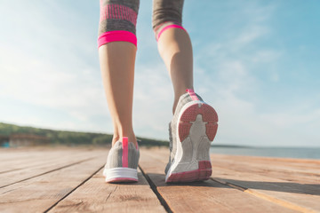 Legs in sneakers close-up. Health and Yoga Concept. Rear view close up strong athletic female legs and running shoes of sport. Sporty young girl practicing yoga. Woman do gymnastics outdoors