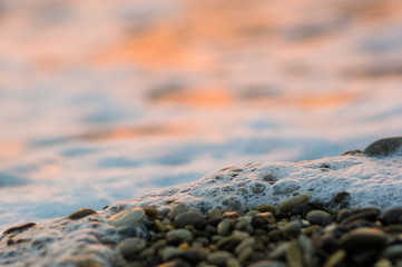 pebble stones on the sea beach, the rolling waves of the sea with foam