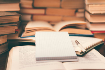 Old open books  and notepad on the table. Piles of of books on reading desk in school study class...