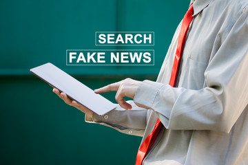 Businessman looking for fake news on tablet.