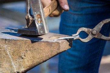blacksmith performs the forging of hot glowing metal on the anvil