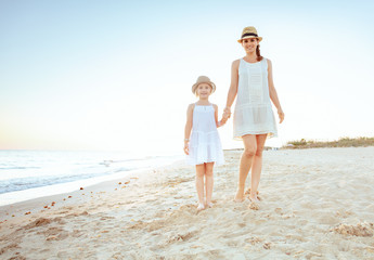happy fit mother and child tourists on seashore in evening