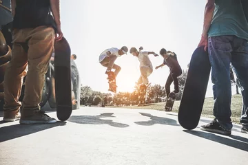 Fototapeten Skaters jumping with skateboard in city skate park - Main focus on center guys heads © DisobeyArt