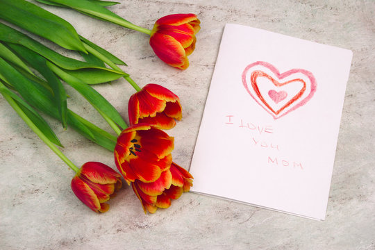 beautiful tulips and handmade card with kid's drawing  for Mother's Day on marble background, top view