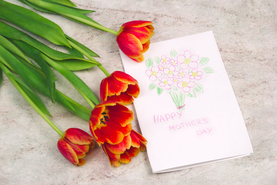 beautiful tulips and handmade card with kid's drawing  for Mother's Day on marble background, top view