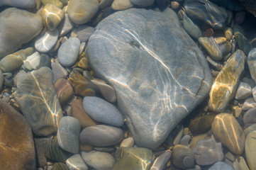 pebble stones on the sea beach, the rolling waves of the sea with foam