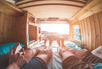 Pov view of happy couple inside vintage wood minivan at sunset around desert - Focus on feet