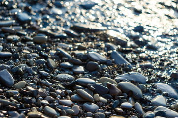 pebble stones on the sea beach, the rolling waves of the sea with foam