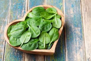Baby spinach leaves in bowl on wooden table. Organic and healthy food.