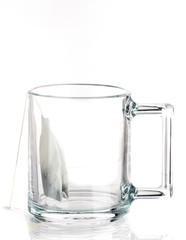 Making tea with sugar from a tea bag in a transparent mug on a white background