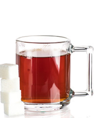 Making tea with sugar from a tea bag in a transparent mug on a white background