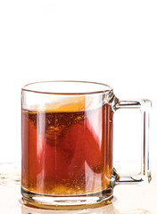 Making tea with sugar from a tea bag in a transparent mug on a white background