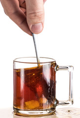 Making tea with sugar from a tea bag in a transparent mug on a white background