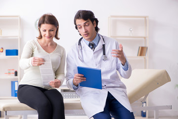 Old pregnant woman visiting young male doctor 