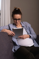 Beautiful pregnant woman with interest studying sites on the tablet