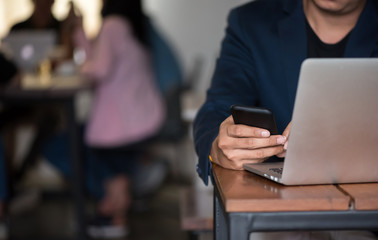 Obraz premium Asian business man working with his smartphone in coffee shop in selective focus.
