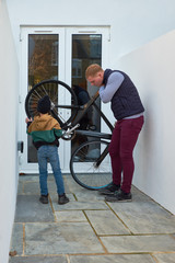 Dad and son are repairing the wheels of a sports bike in the backyard of the house