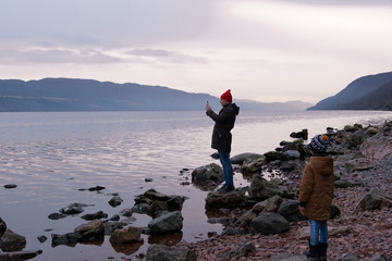 The boy watches as dad photographs the lake at sunset
