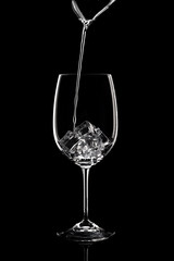 Wine pours into a glass with ice   on a black background.