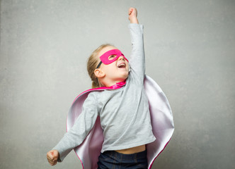 Little girl pretending that she is flying wearing a cloak and mask - Powered by Adobe
