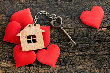 House key in heart shape with home keyring on wood background decorated with mini hearts - 254207428