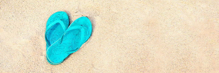 Blue pair of flip flops on the beach, panoramic summer concept
