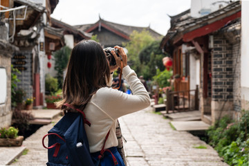 Young woman traveler walking and photographing at lijiang old town in Yunnan province, China