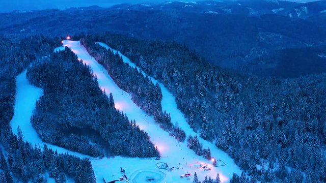 Ski slope and frozen forest in Borsec sports resort, aerial view in the evening.