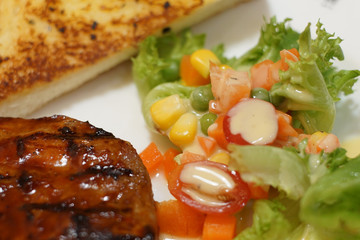 Grilled steak, baked potatoes and vegetables on the table