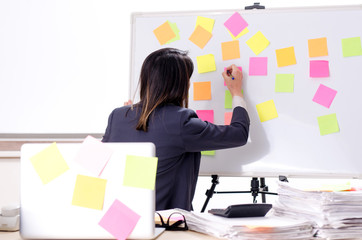 Young female employee in conflicting priorities concept 
