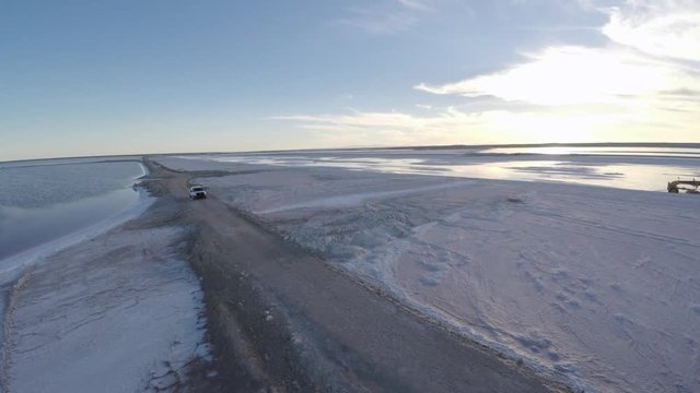 Aerial rolling drone shot shot of a pickup in the salt flats by solar evaporation in Guerrero Negro, Ojo de Liebre lagoon, Biosphere Reserve of El Vizcaino, Baja California Sur.