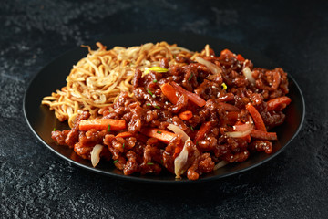egg noodles with bean sprouts and Crispy shredded beef on black plate