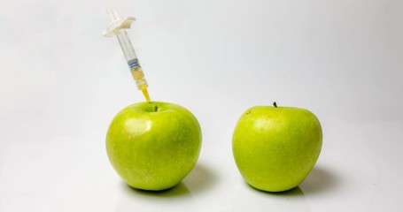 a fresh apple with a syringe and a decaying apple during, time laps, the concept of slowing down aging using medical and chemical methods - Powered by Adobe