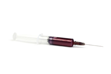  5 ml syringe with red liquid lies on the white background. The concept of blood sucking. 