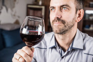 Man tasting a glass of red wine. Selective focus.