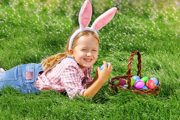 A cute little baby girl collects Easter eggs in the garden.