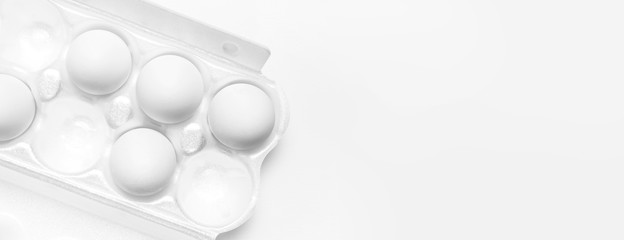 White chicken eggs in white packaging on light background top view flat lay copy space. Eggs in box, natural healthy food and organic farming concept. Creative food minimalistic background, Easter